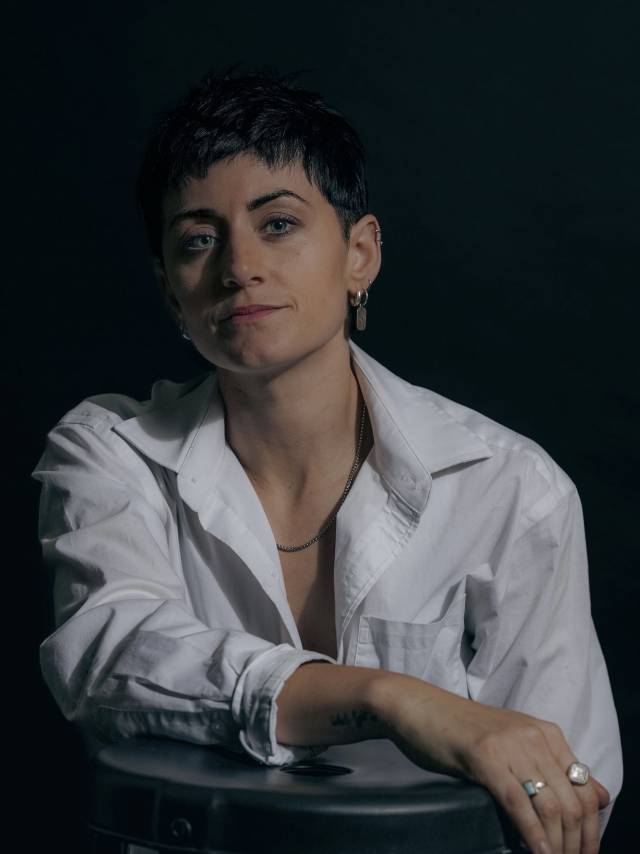 person in white button down and short black hair looking at the camera