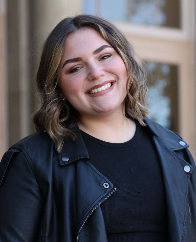 a fair skinned woman with black leather jacket and black top smiling