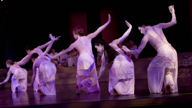 a group of people painted white and wearing white clothing pose with their arms outstretched