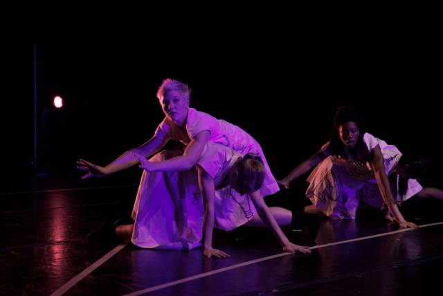 two women balance on the backs of two women who are on all fours