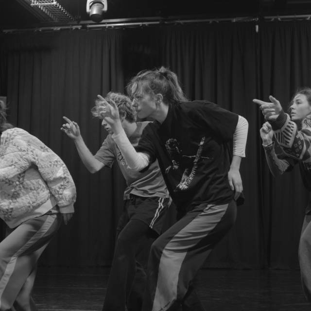 5 dancers in profile hunch over while pointing a finger outward