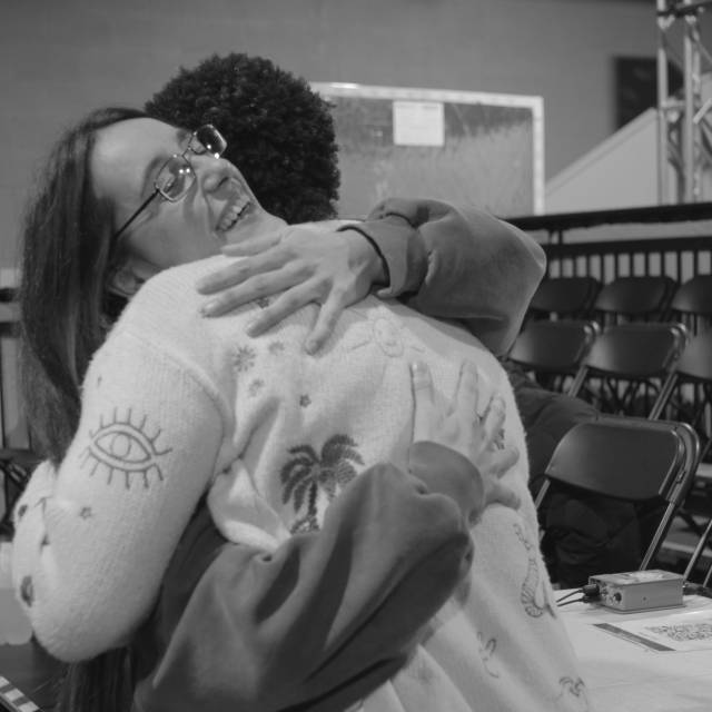 A woman smiles while embracing another person