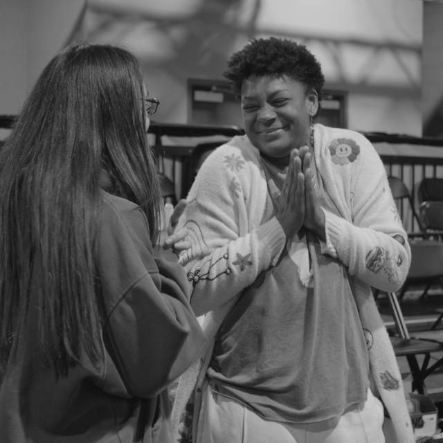 a brown skinned woman smiles with glee at another person