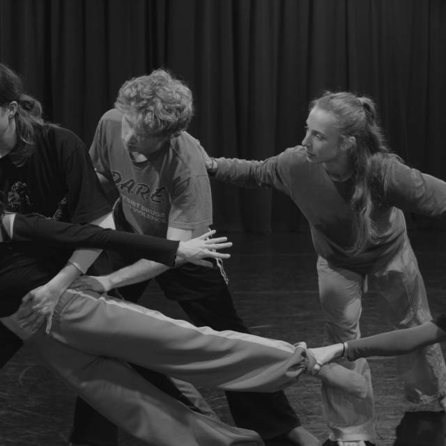 5 people are connected by limbs while holding one of the dancers off kilter
