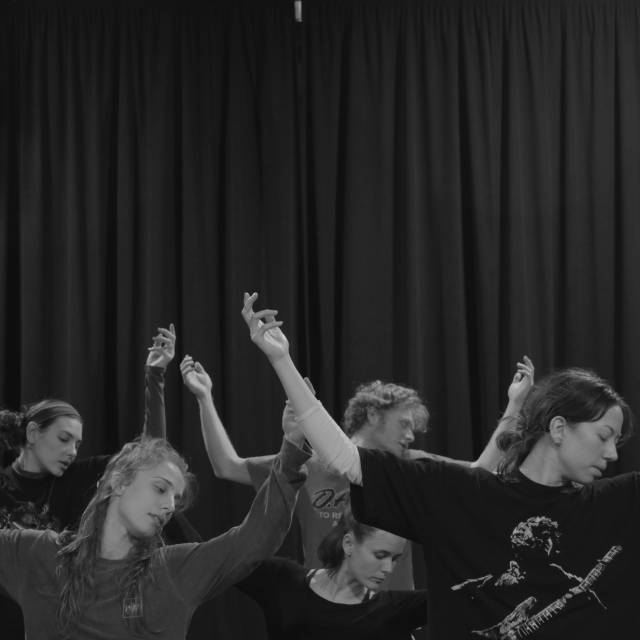 5 dancers grouped together with their bent arms raised 