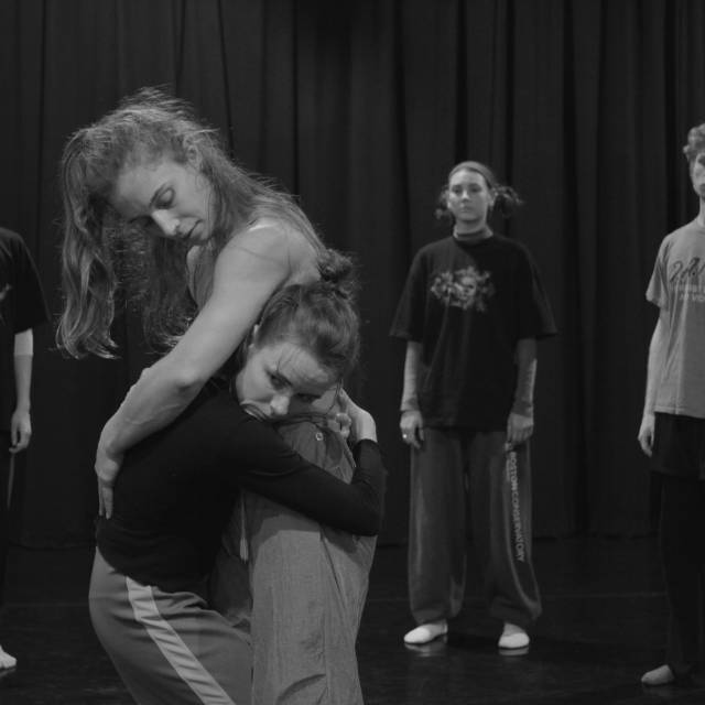 One dancer embraces another in an unconventional-looking hug