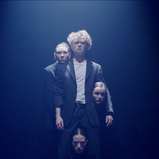 a man stands with three extra heads appearing around his body