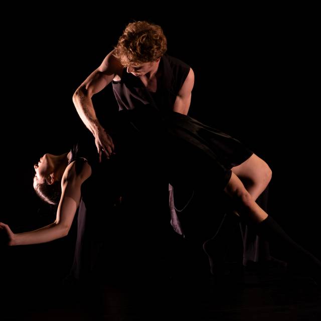 a man holds a woman as she lays back and stretches out her arms