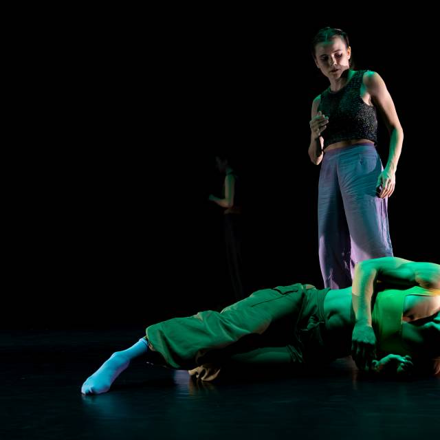 woman on the floor looking upward while another woman stand over her watching