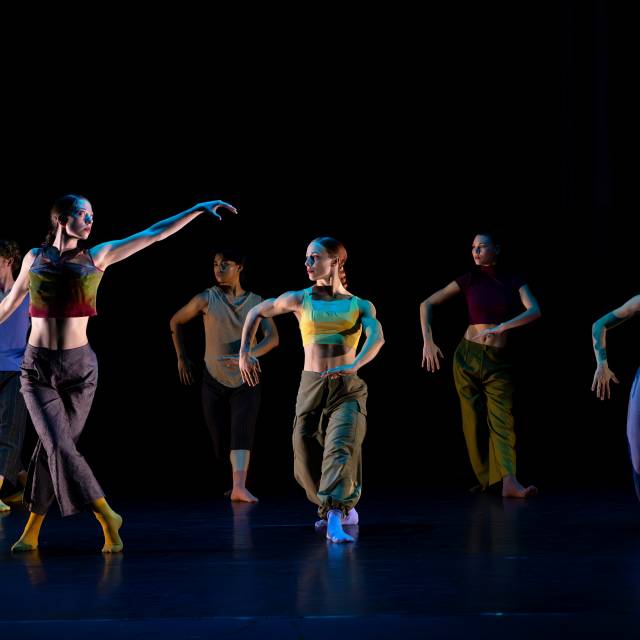 group of 5 pose with arms at a right angle while woman has her arms outstretched
