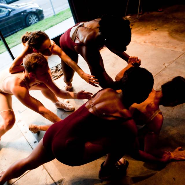 four people from fair skinned to brown skinned tones reach down toward another person on the ground