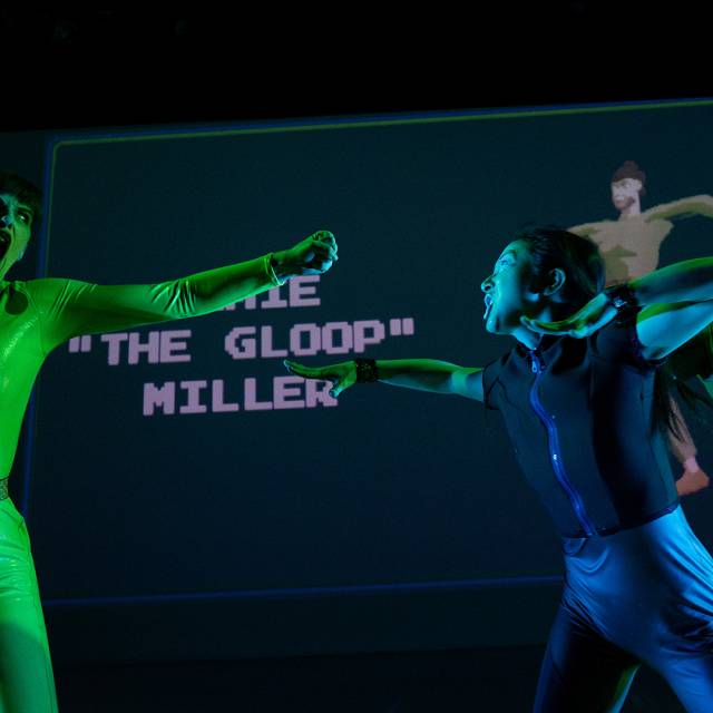 a figure in green and a figure in black and blue charge toward each other