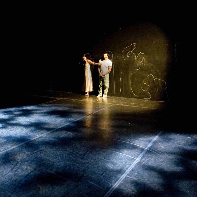 two figures up against a black wall with chalkboard figure drawings