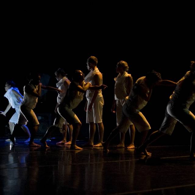 a group of figures wearing white lunging while in silhouette