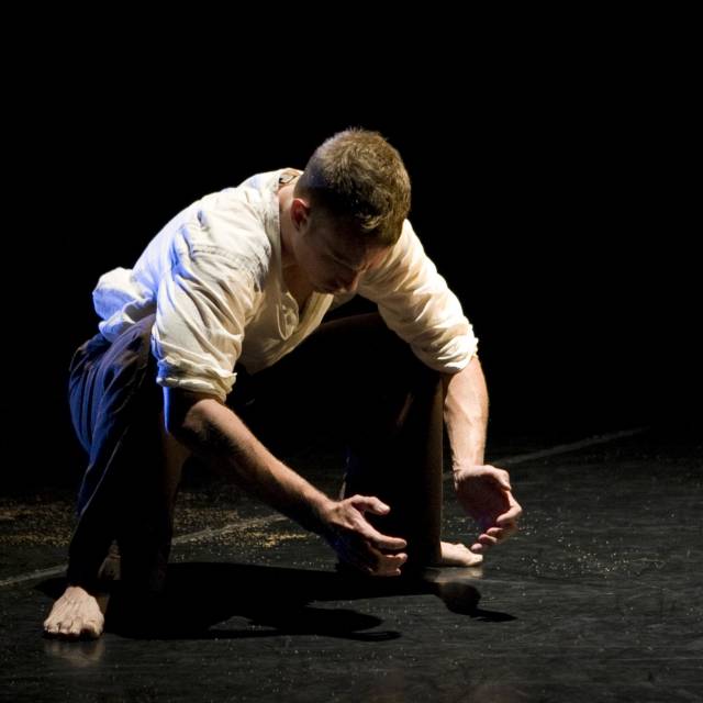 fair-skinned main wearing a white button down and brown pants is in a deep squat