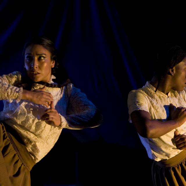 a medium-skinned woman and a brown-skinned woman clutch face away from each other while clutching their chests