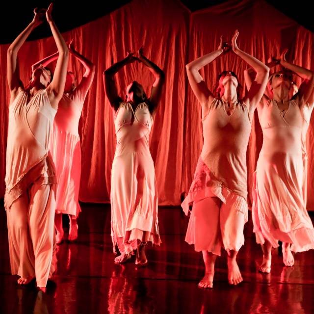 six women with their heads raised and their arms above their heads in a meditative position