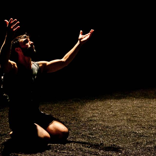 a man kneels with his arms outstretched