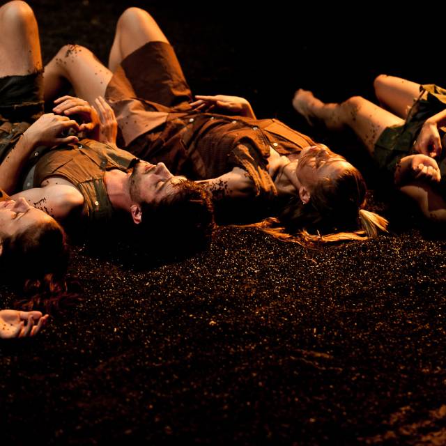 4 people lay on their backs in black sand
