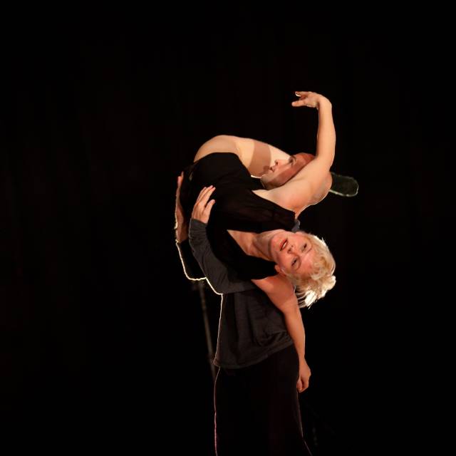 a man lifts a woman whose body wraps around his