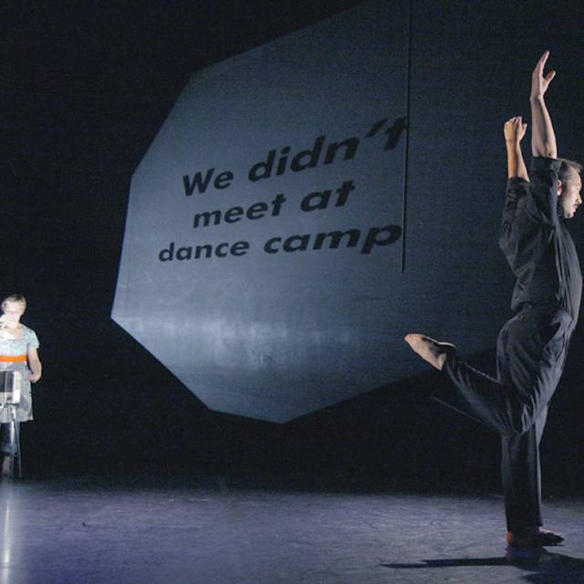 text projected onto a wall while a man stands on one leg with his arms raised