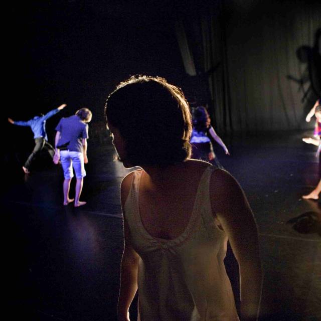a woman looks behind her at a group of people dancing