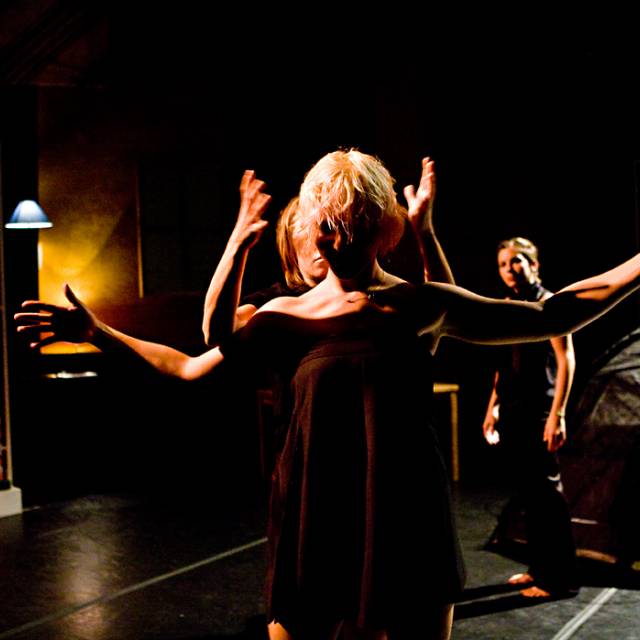 a fair skinned woman has her arms outstretched while a separate set of fair skinned hands hover on either side of her head