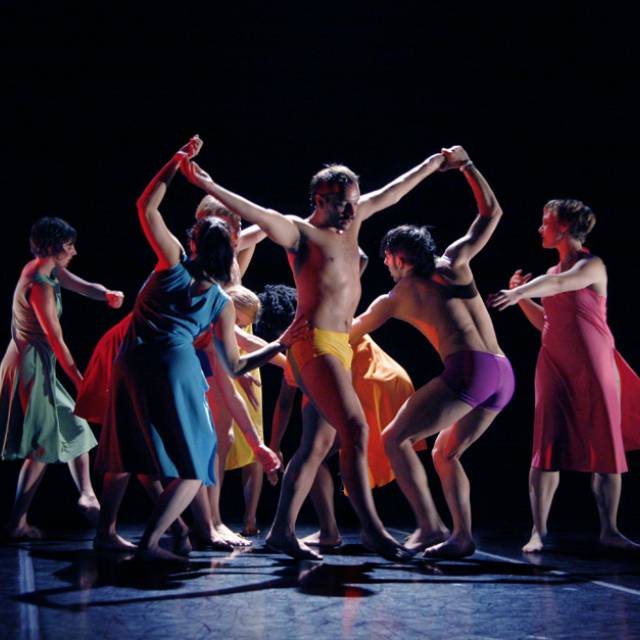 a group of dancers in brightly colored costumes with limbs intertwined