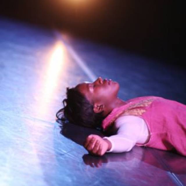 a brown skinned woman lays on the ground with her arms outstretched