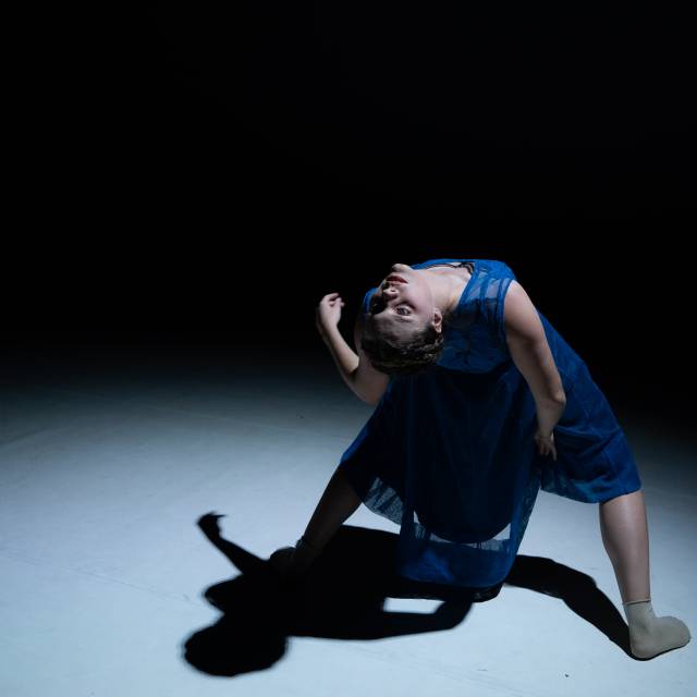 woman in blue dress bends backwards