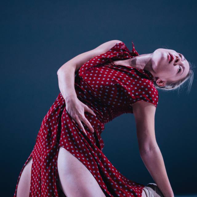 woman kneeling in red dress leans back 