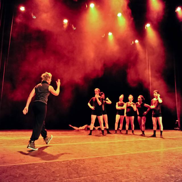 woman gives instruction to 6 dancers