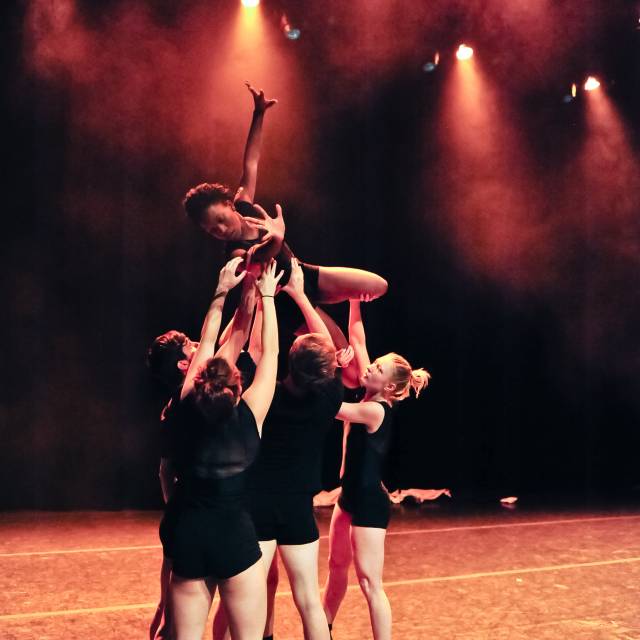 a group of people lift a woman. her arms extend outward