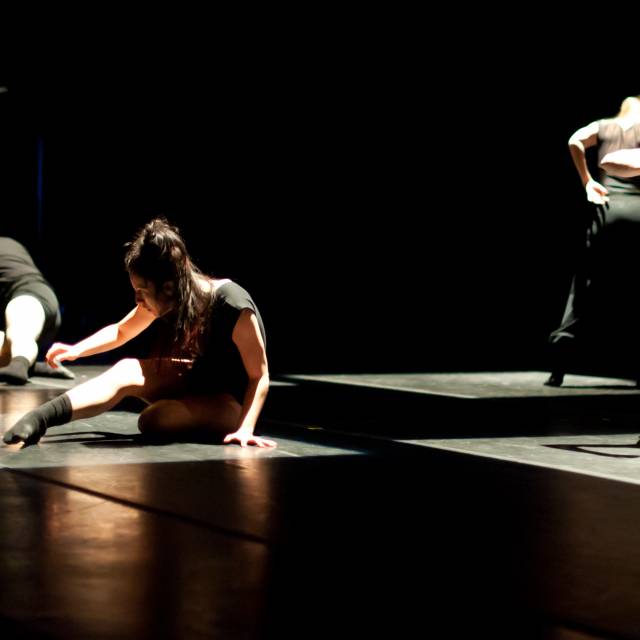 4 dancers mid-movement in square spotlights 