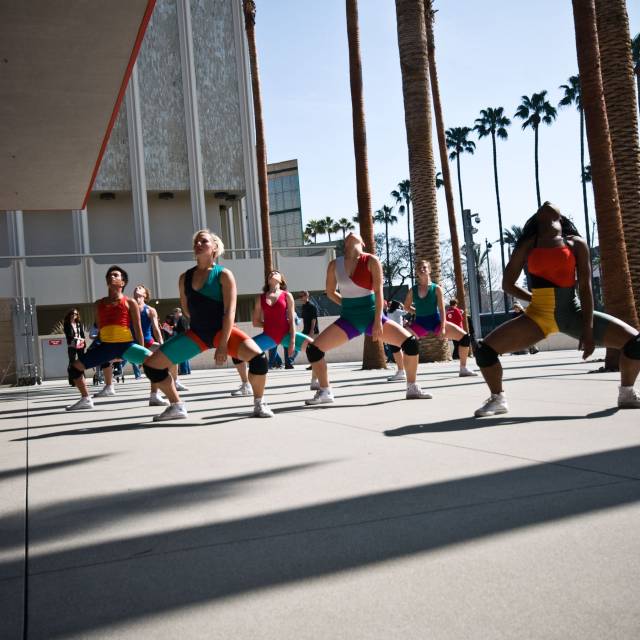 a group of people wearing brightly colored clothes plie in second