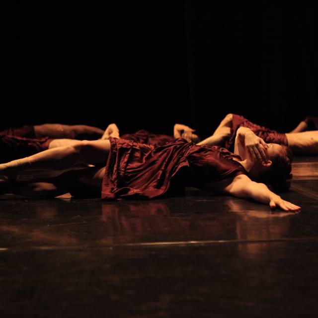 woman lays on the floor with one hand across her mouth