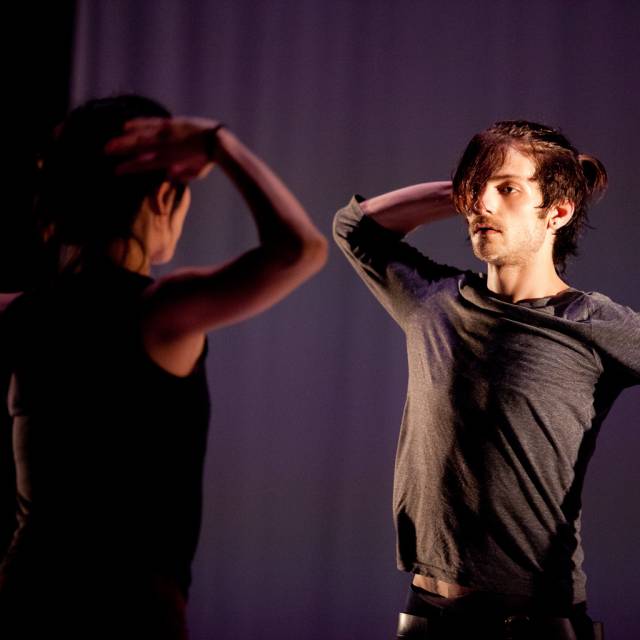 man and woman face off with one arm on their head