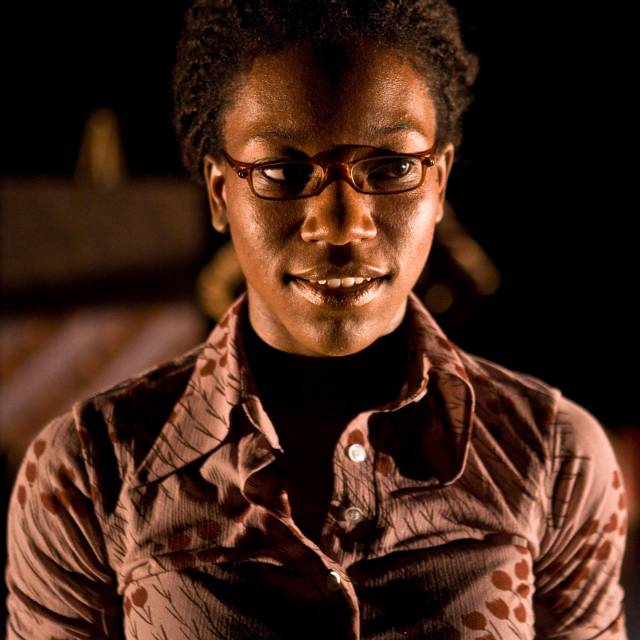 a woman looks off in the distance with a faint smile