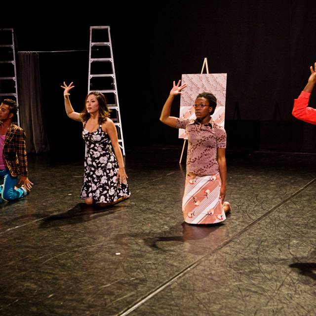 a man and three women sit upright on their knee while raising their right hand