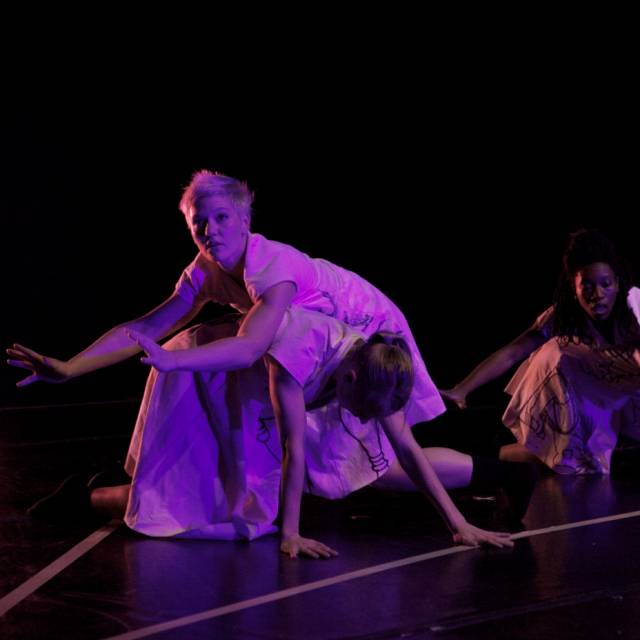 two women balance on the backs of two women who are on all fours