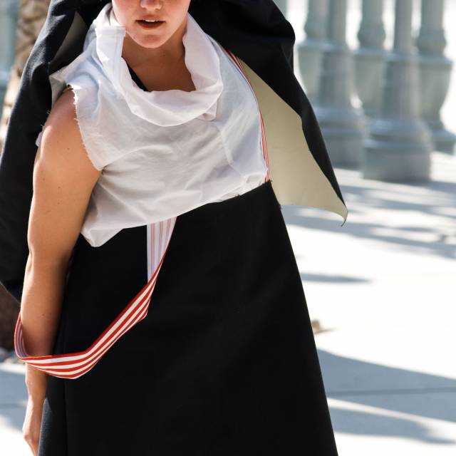 woman wearing an oversized suit raises one arm