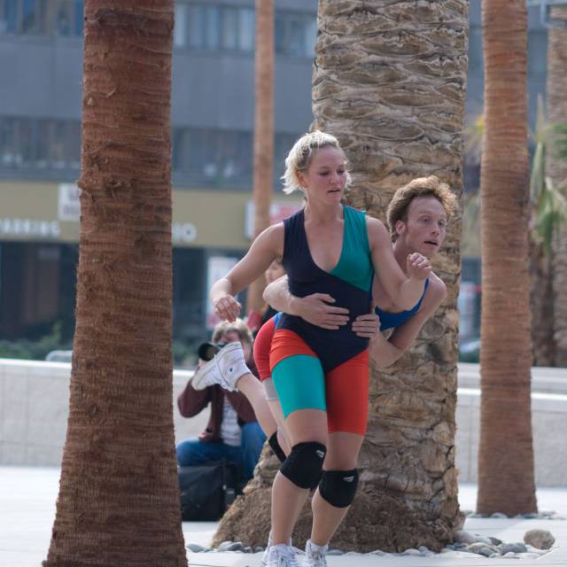 a pair of people stumble forward wearing brightly colored outfits