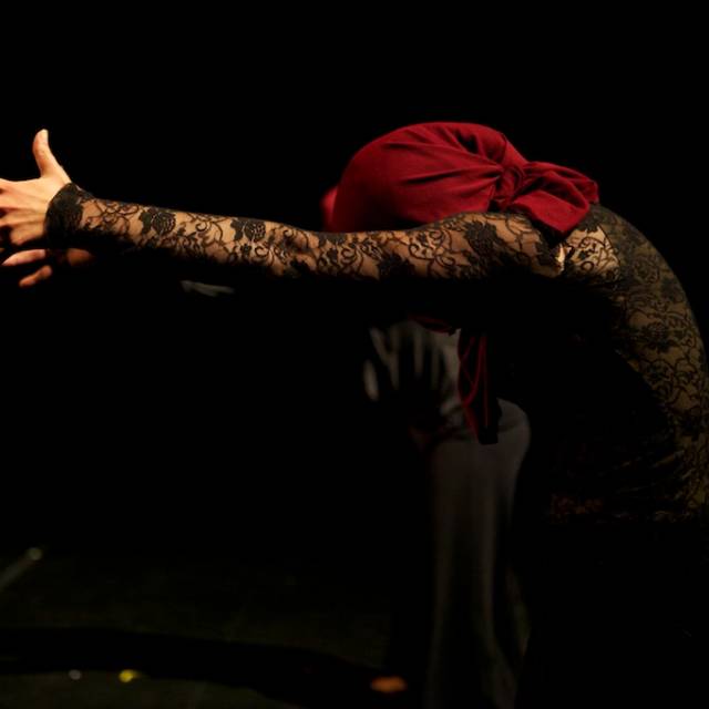 profile a person with their arms outstretched, face covered with maroon cloth
