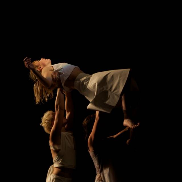 a woman wearing white is lifted into the air by two people