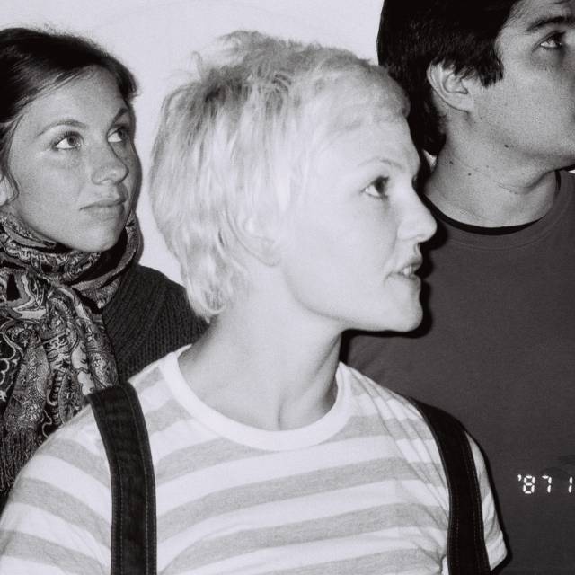 two woman and a man look off screen