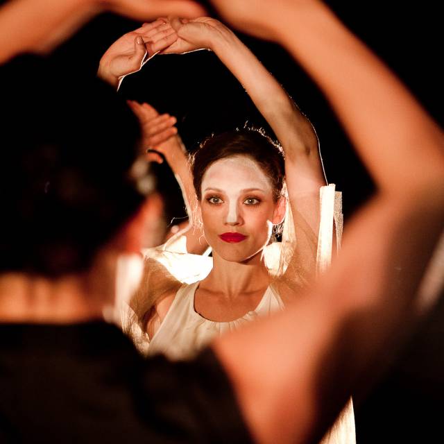 a woman stands with her arms above her head in a diamond shape
