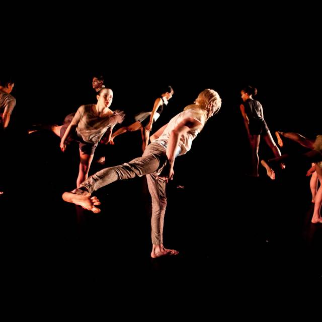 a group of dancers stand in arabesque with their foot flexed