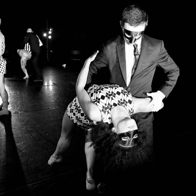 a man dips a woman who is wearing a mask