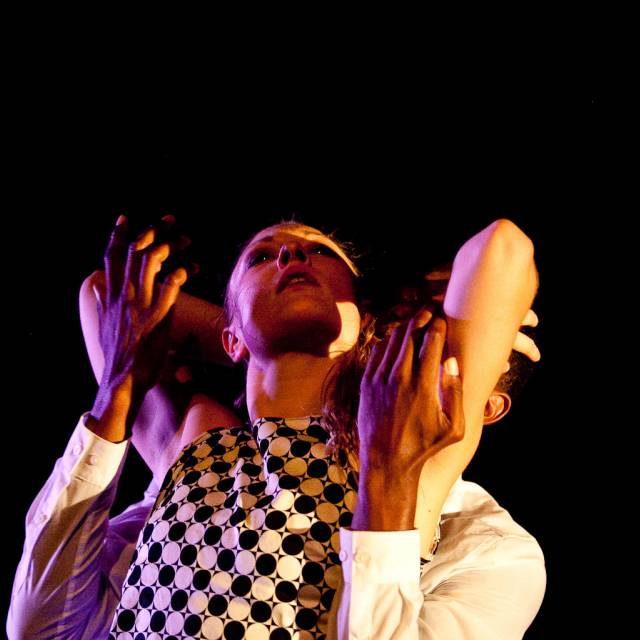 a man cradles a woman's elbows from behind
