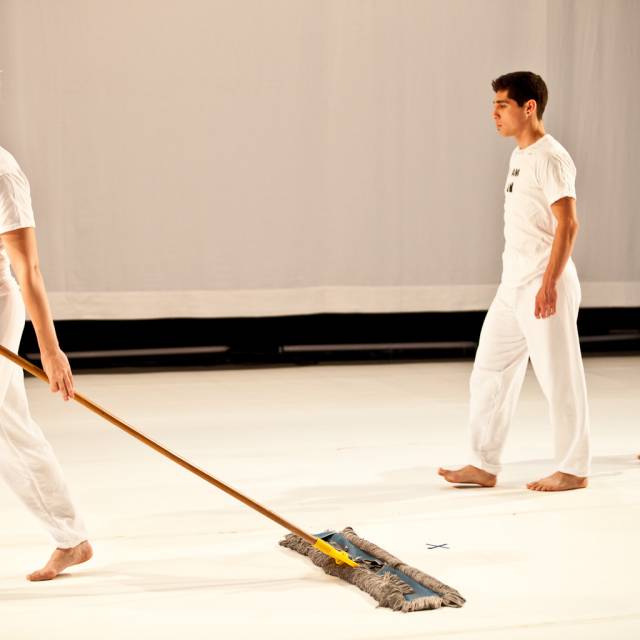 a woman drags a floor mop and a man follows behind her